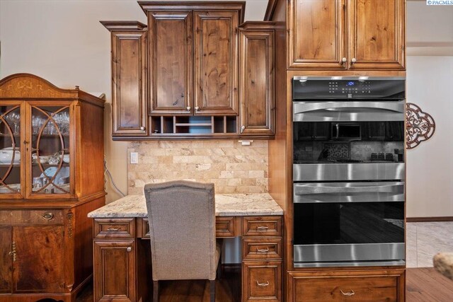 404 S Georgia St, Kennewick, WA 99338 - kitchen with stainless steel double oven, built in desk, light stone countertops, and tasteful backsplash