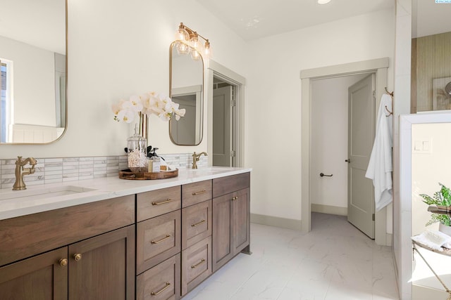 full bathroom with double vanity, marble finish floor, baseboards, and a sink