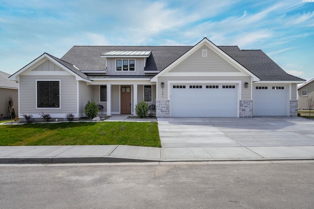 view of front of property with an attached garage, concrete driveway, board and batten siding, a standing seam roof, and a front yard