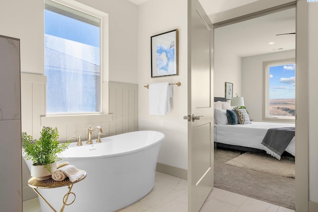 ensuite bathroom with marble finish floor, connected bathroom, and a freestanding bath