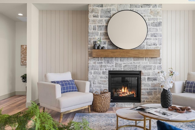 living area with a glass covered fireplace, baseboards, and wood finished floors