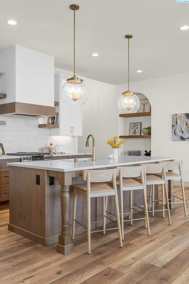 kitchen featuring light wood-type flooring, premium range hood, white cabinets, and open shelves