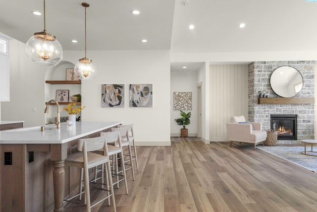 kitchen with a breakfast bar, a fireplace, light wood finished floors, recessed lighting, and light countertops