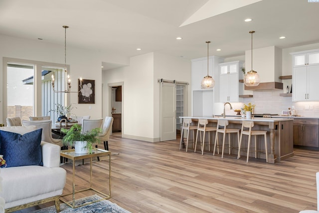 living area featuring a barn door, a chandelier, light wood-style flooring, and recessed lighting