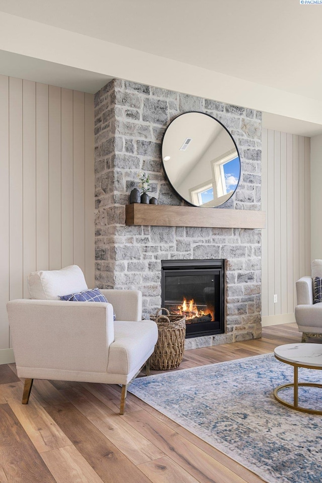 living area featuring a fireplace, visible vents, and wood finished floors