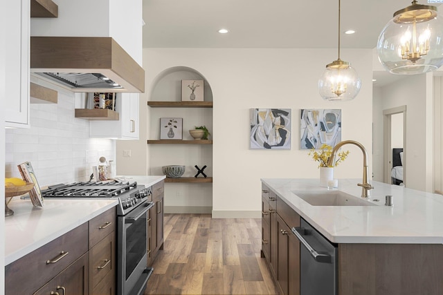 kitchen featuring light wood-style flooring, custom range hood, appliances with stainless steel finishes, open shelves, and a sink