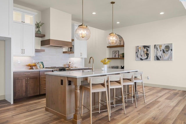 kitchen with light countertops, white cabinets, and custom range hood