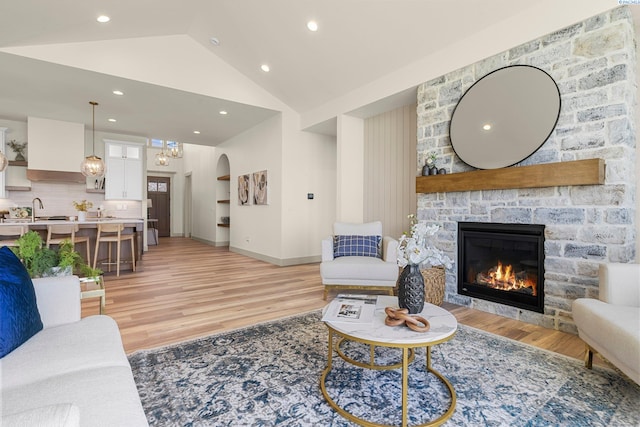 living area with baseboards, arched walkways, light wood-style flooring, a fireplace, and recessed lighting