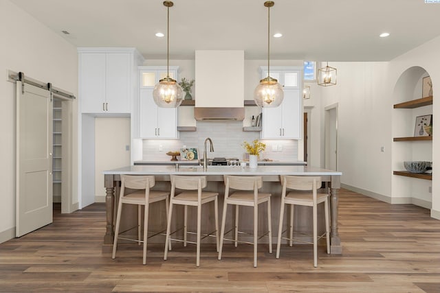 kitchen featuring white cabinets, light wood finished floors, a barn door, and light countertops