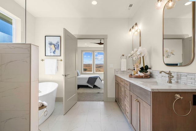 bathroom with marble finish floor, double vanity, visible vents, a sink, and a freestanding tub