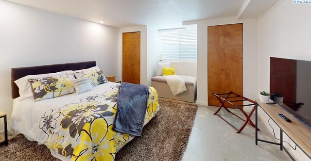 bedroom featuring concrete flooring and multiple closets