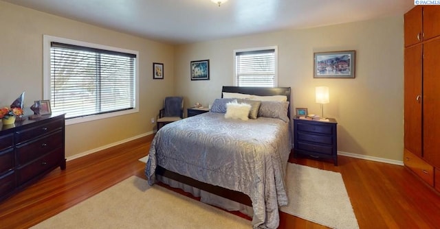 bedroom with multiple windows and dark hardwood / wood-style flooring