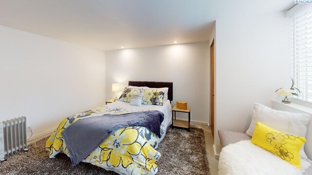 carpeted bedroom featuring multiple windows and radiator heating unit