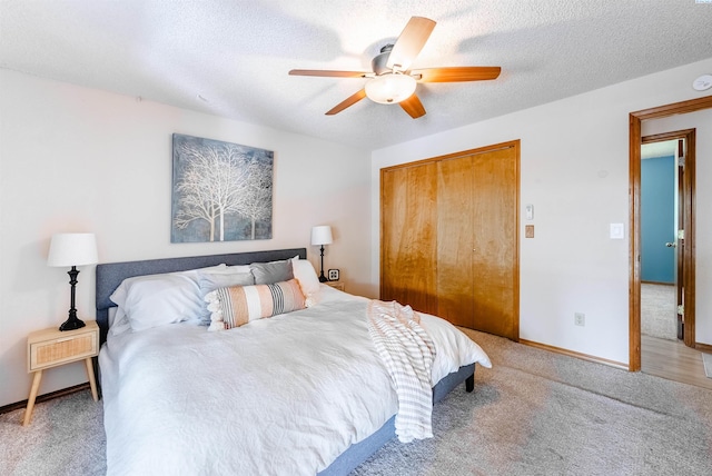 bedroom with a textured ceiling, ceiling fan, carpet floors, baseboards, and a closet