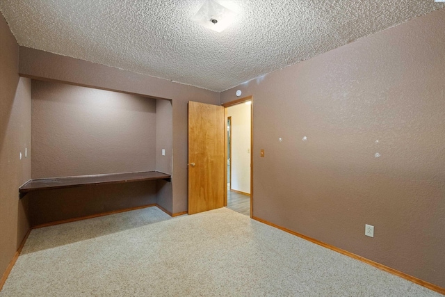 unfurnished bedroom with baseboards, carpet floors, a textured ceiling, and a textured wall