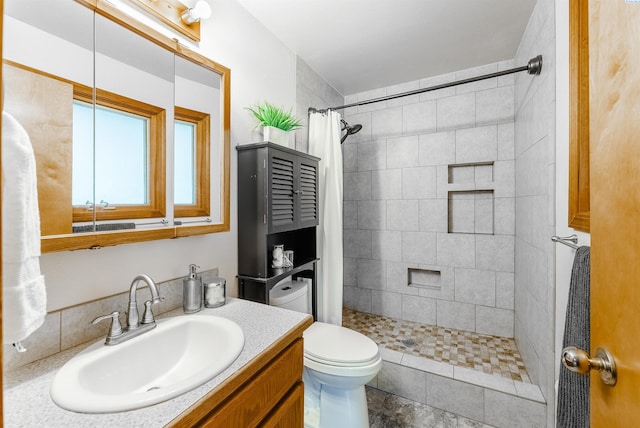 bathroom featuring toilet, a tile shower, and vanity