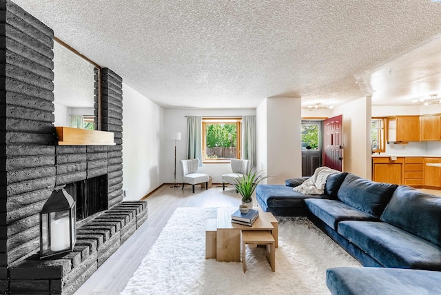 living area with a textured ceiling, light wood-style flooring, and a fireplace