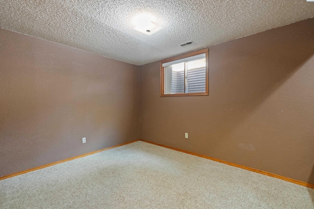 carpeted empty room with a textured ceiling, visible vents, a textured wall, and baseboards
