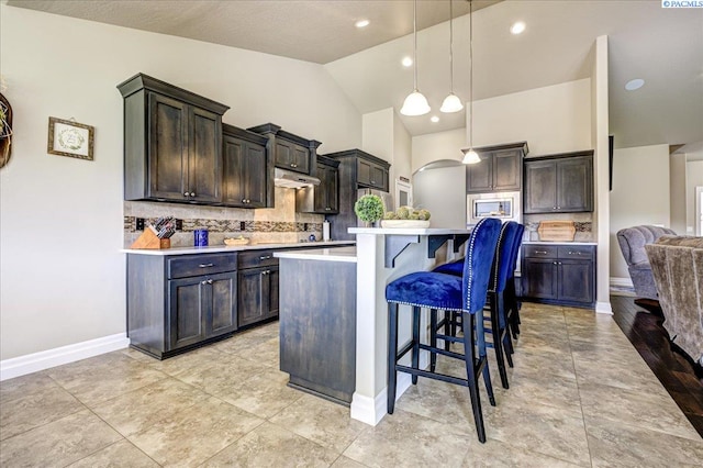 87021 Summit View Dr, Kennewick, WA 99338 - kitchen with a breakfast bar area, light countertops, decorative backsplash, baseboards, and vaulted ceiling