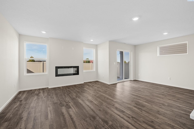 688 S Zeelar St, Kennewick, WA 99336 - unfurnished living room with dark wood-style flooring, a glass covered fireplace, baseboards, and recessed lighting