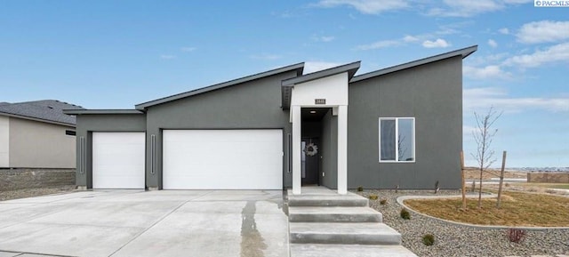 view of front of home with driveway, an attached garage, and stucco siding