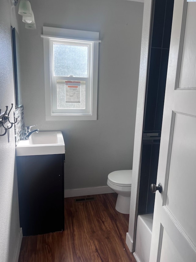 bathroom featuring baseboards, visible vents, toilet, wood finished floors, and vanity