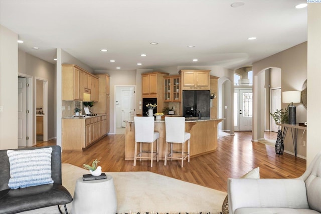 1209 W Canyon Lakes Dr, Kennewick, WA 99337 - kitchen featuring black fridge, arched walkways, glass insert cabinets, light brown cabinets, and light wood-style floors