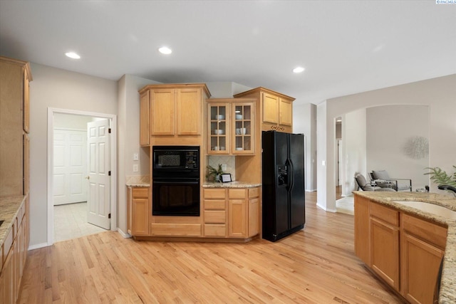 1209 W Canyon Lakes Dr, Kennewick, WA 99337 - kitchen featuring black appliances, arched walkways, light wood-style flooring, glass insert cabinets, and light stone counters