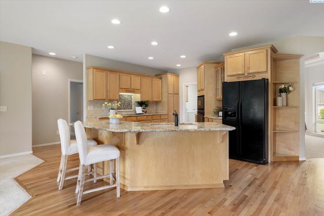 1209 W Canyon Lakes Dr, Kennewick, WA 99337 - kitchen featuring black fridge with ice dispenser, light brown cabinetry, a kitchen bar, light wood-style floors, and recessed lighting