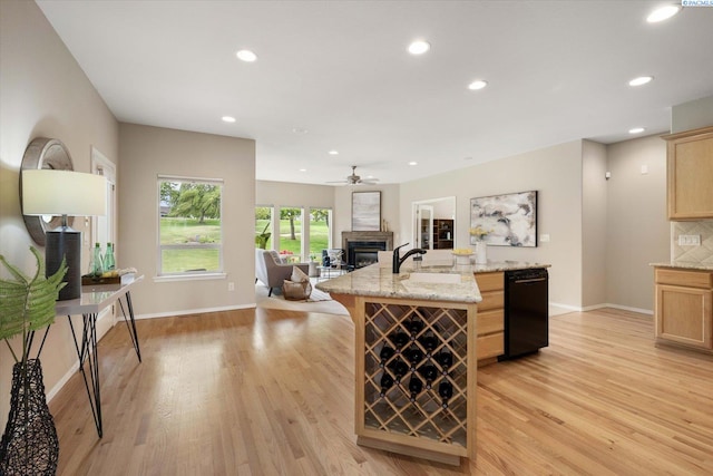 1209 W Canyon Lakes Dr, Kennewick, WA 99337 - kitchen with black dishwasher, open floor plan, light brown cabinetry, light wood-type flooring, and a kitchen island with sink