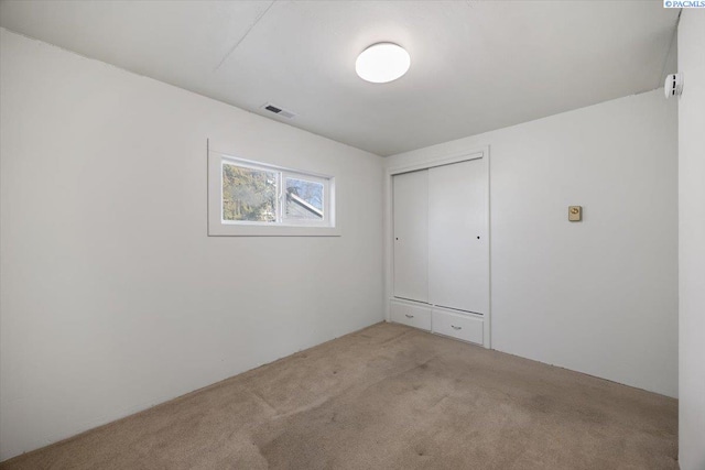 unfurnished bedroom featuring light colored carpet and a closet