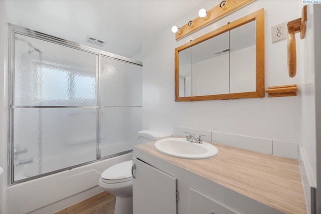 full bathroom with toilet, vanity, shower / bath combination with glass door, and hardwood / wood-style floors