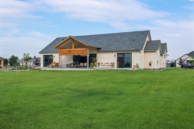 7004 Ricky Rd, Pasco, WA 93301 - back of house featuring a yard, a shingled roof, stucco siding, and a patio area