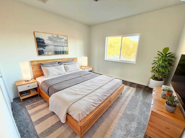 bedroom featuring dark carpet and baseboards