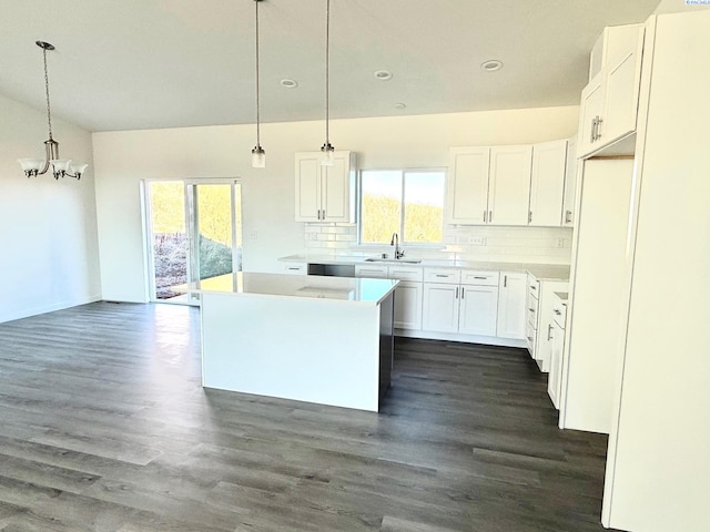 kitchen featuring white cabinets, a kitchen island, hanging light fixtures, light countertops, and backsplash