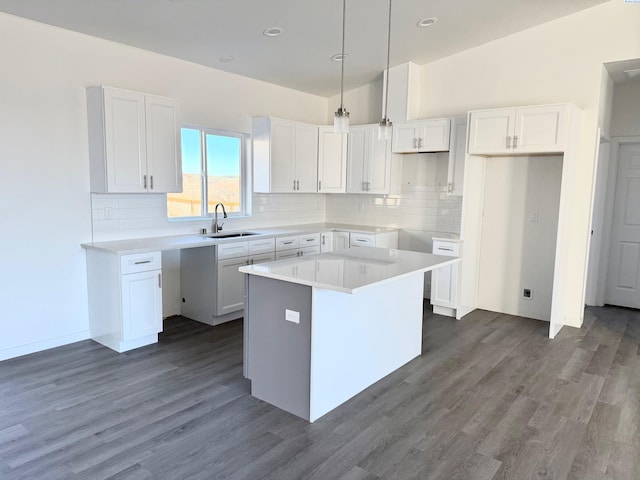 kitchen featuring a kitchen island, white cabinetry, light countertops, and a sink