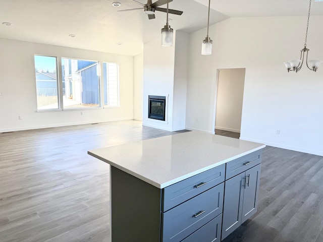 kitchen with a glass covered fireplace, a kitchen island, open floor plan, dark wood finished floors, and decorative light fixtures