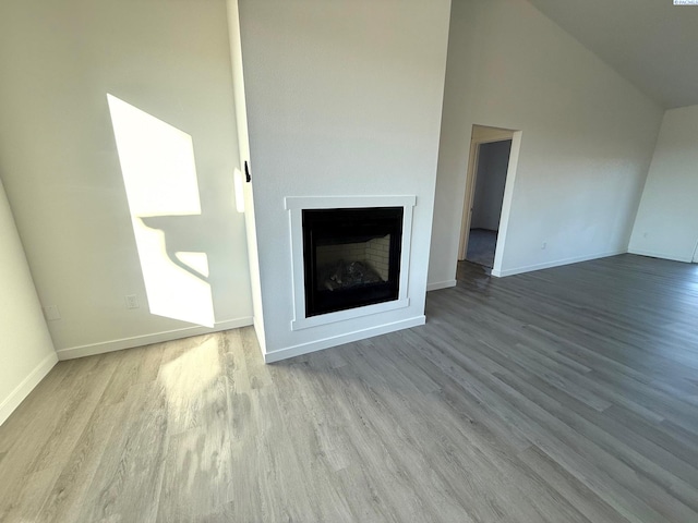 unfurnished living room with high vaulted ceiling, light wood-style flooring, a fireplace, and baseboards