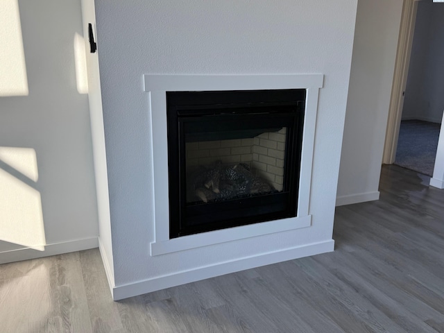 details featuring a fireplace, wood finished floors, and baseboards