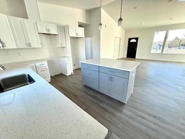 kitchen with pendant lighting, a kitchen island, a sink, and white cabinets