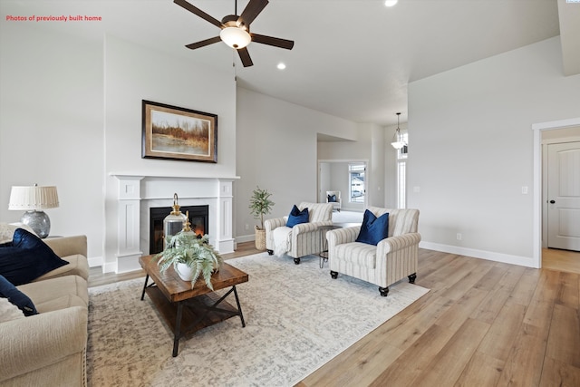 living room with baseboards, a glass covered fireplace, ceiling fan, light wood-style floors, and recessed lighting