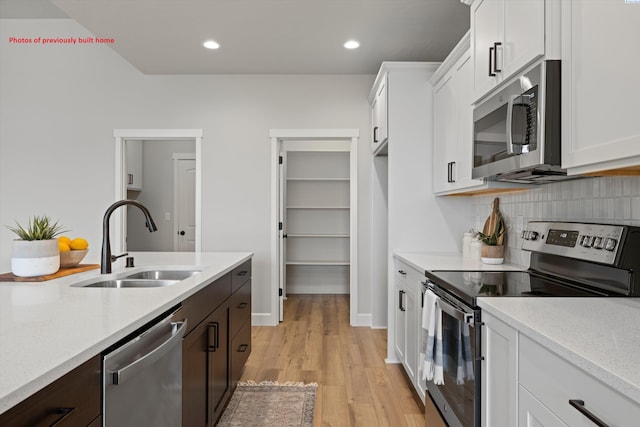 kitchen with a sink, stainless steel appliances, light countertops, and white cabinets