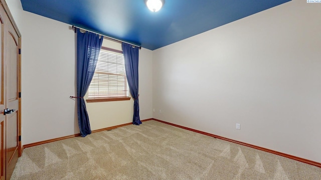 empty room featuring carpet and baseboards