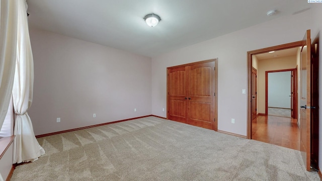 unfurnished bedroom featuring light carpet, baseboards, and a closet