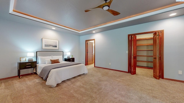 bedroom featuring light colored carpet, baseboards, recessed lighting, a tray ceiling, and ceiling fan