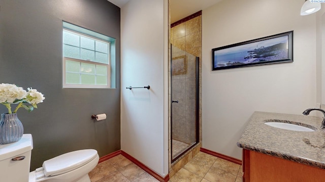 full bath featuring toilet, a shower stall, vanity, baseboards, and tile patterned floors