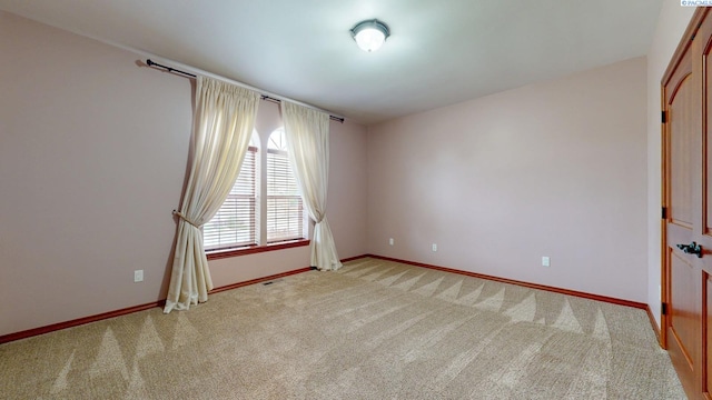 empty room featuring light colored carpet and baseboards