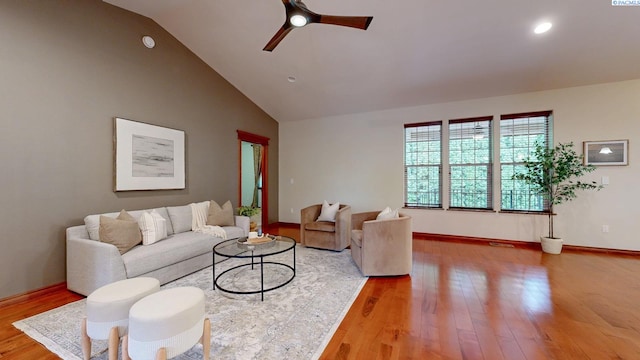 living area featuring light wood-type flooring, a ceiling fan, baseboards, and high vaulted ceiling