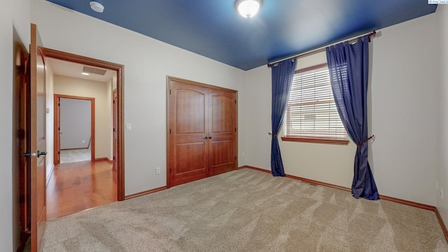 unfurnished bedroom with carpet, baseboards, and a closet