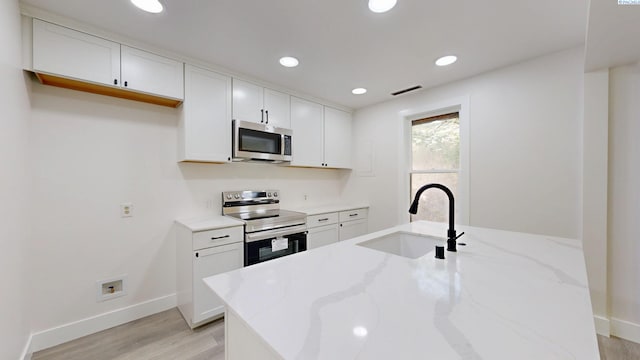 715 NW Ritchie St, Pullman, WA 99163 - kitchen featuring appliances with stainless steel finishes, light wood-type flooring, light stone countertops, white cabinetry, and recessed lighting